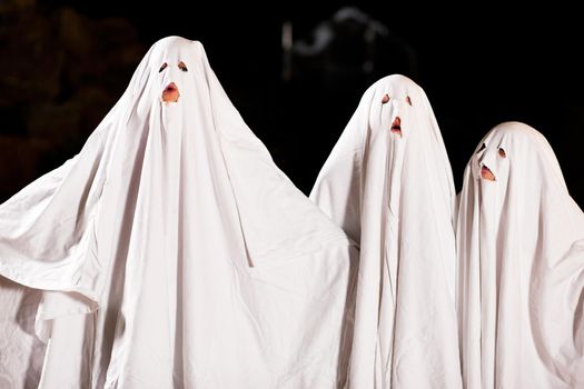 Three very, very scary spooks - kids dressed as ghosts - on Halloween or for carnival or a costume party