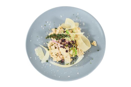 Top view close up of porridge with parmesan and herbs in beautiful blue plate on white background. Concept of healthy diet maintain body weight or emaciation. 