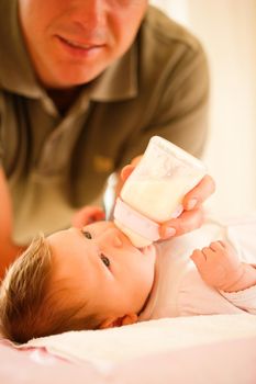 Father is feeding his baby with a bottle; very tranquil scene