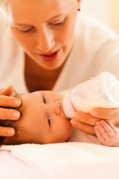 Mother is feeding her baby with a bottle; very tranquil scene