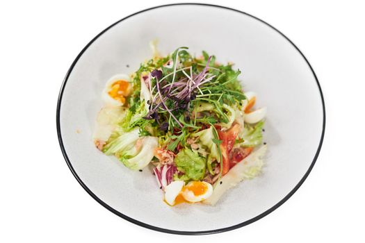 Top view close up of vegetables salad with greens,eggs and tomatoes on white background. Concept of proper nutrition for weight loss at home. 