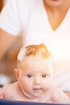 Mother is bathing her baby, just hands