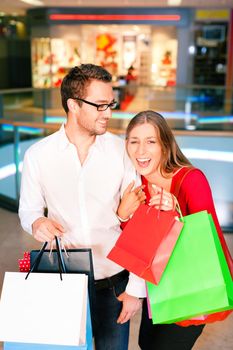 Couple - man and woman - in a shopping mall with colorful bags simply having fun