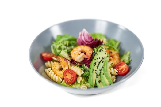 Close up of modern and beautiful plate with appetizing pasta in vegetables and with seafood on white background. Concept of delicious dish with healthy ingredients for body weight maintenance.