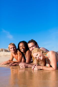Group of Four friends - men and women - on the beach having lots of fun in their vacation