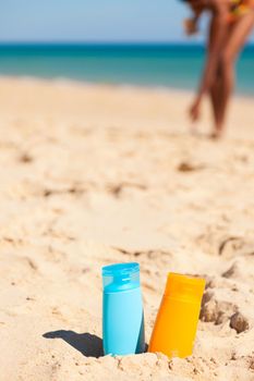 Two bottles of suncream in sand at the beach - lots of protection