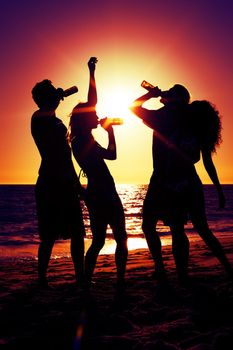 People (two couples) on the beach having a party, drinking and having a lot of fun in the sunset (only silhouette of people to be seen, people having bottles in their hands with the sun shining through)