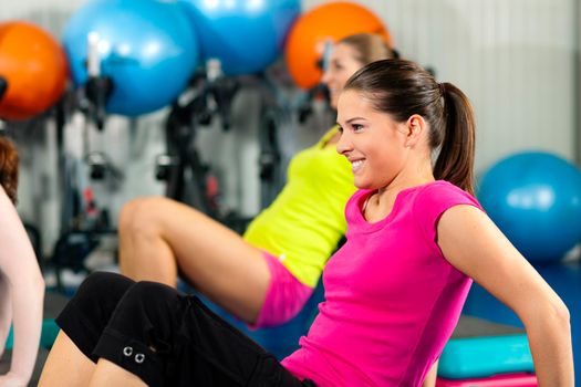 Fitness People in gym on step board; strengthening the abdominal muscles