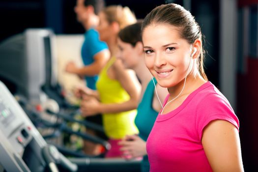 Running on treadmill in gym - group of women and men exercising to gain more fitness