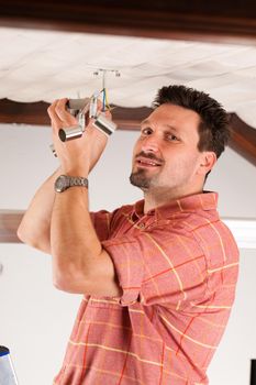 Worker is installing a luster in a Haus on the ceiling