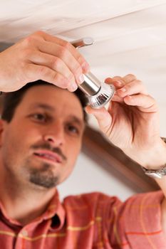 Worker is installing a luster in a Haus on the ceiling