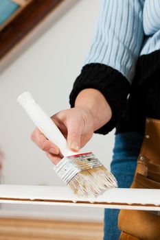 woman - only hands to be seen - is painting in her house; presumably she is renovating