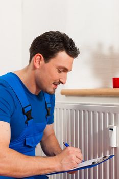 Technician reading the heat meter to check consumption