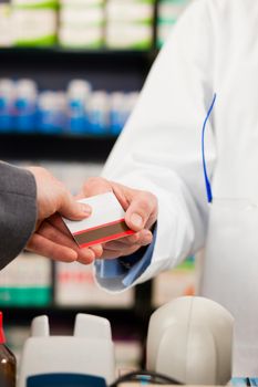 Pharmacist with customer in pharmacy; the customer pays with credit card; from both only the hands are seen