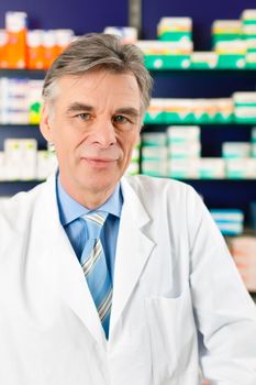 Portrait of Pharmacist in a pharmacy, he is wearing glasses and is very experienced and trustworthy