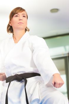 Woman in martial art training in a gym, she is wearing a black belt