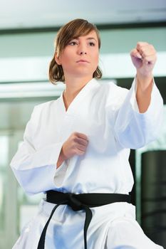 Woman in martial art training in a gym, she is wearing a black belt