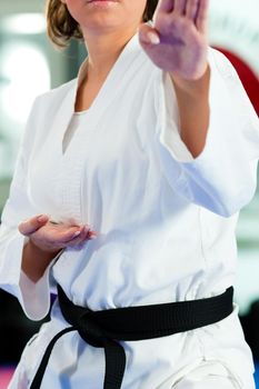 Woman in martial art training in a gym, she is wearing a black belt