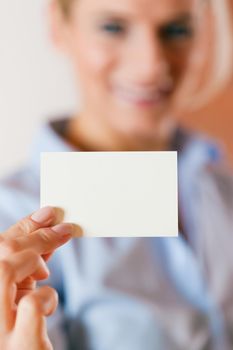 Business woman is handing her business card over - focus on the card
