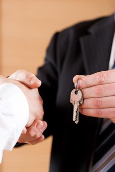 Two businessperson shaking hands; only hands to be seen and a key is be given