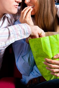 Couple in cinema theater watching a movie, they eating popcorn, close-up