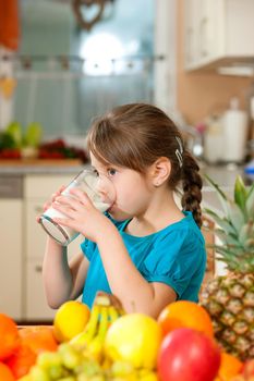 Healthy eating - Child drinking milk, lots of fresh fruit on the table in front