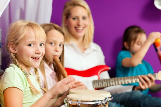 Family - Children and mother - making music, they are practicing playing guitar, bongo and flute
