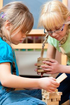 Children - sisters - playing at home with bricks