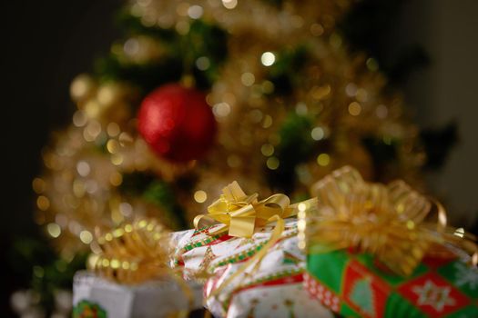 Stacks of Christmas Presents Under a Christmas Tree with Defocused Lights.