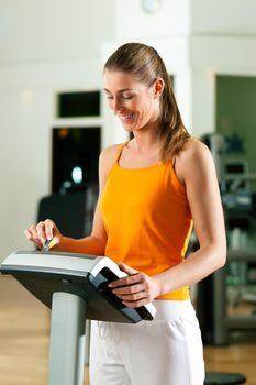 Woman in gym or health club reading her training plan which is stored on a modern key system