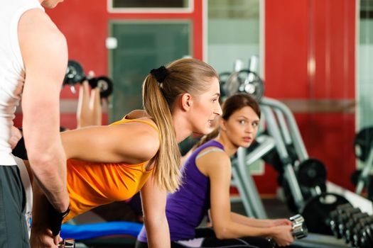 People in gym or fitness club exercising with weights together