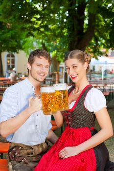 Couple with beer stein and traditional clothes in a beer garden