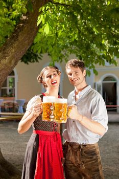 Couple with beer stein and traditional clothes in a beer garden