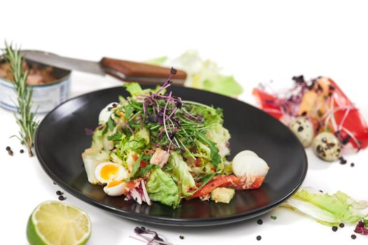 Close up of appetizing salad with tuna in its own juice and fresh greens on white background. Concept of balanced diet with vegetables and proteins at home. 