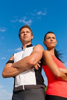Fitness - Young sportive couple in front of a blue sky on a beautiful summer day outdoors