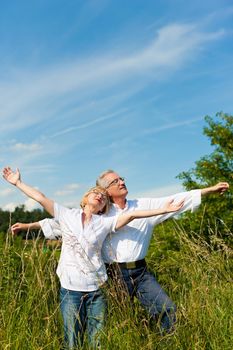 Happy mature couple - senior people (man and woman) already retired - having fun in summer in nature