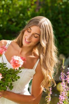 Gardening in summer - happy woman with flowers in her garden