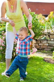 Family - mother and child playing in garden on a beautiful summer day