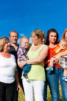 Family and multi-generation - mother, father, children and grandmother having fun on meadow in summer