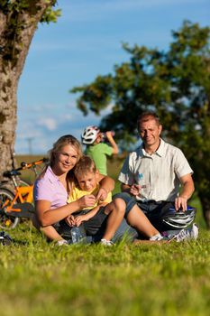 Happy family (father, mother and two sons) on getaway with bikes - they have a break