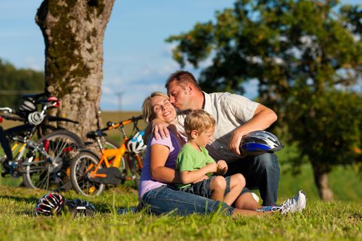 Happy family (father, mother and son) on getaway with bikes - they have a break