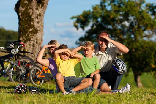 Happy family (father, mother and two sons) on getaway with bikes - they have a break