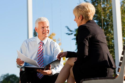 Business Coaching outdoors - man and woman in coaching discussion