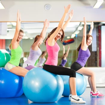 Fitness - Young women doing sports training or workout with gymnastic ball in a gym