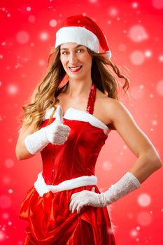 Attractive young woman in Santa Claus costume with thumbs up okay approval snow flakes on isolated red background Xmas celebration festive winter smiling happy