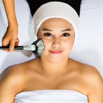 Young Asian Woman having a mask or cream applied in the course of a beauty treatment