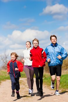 Family, mother, father and children are running or jogging for sport outdoors