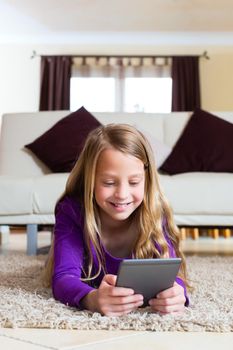 Family - child reading an E-Book lying on the floor at home