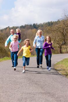 Family (mother, father and four children) is running outdoors in spring