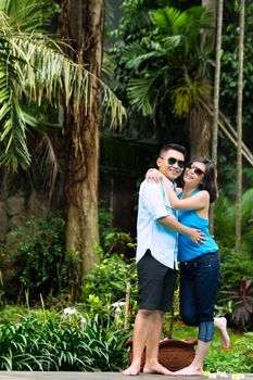 Indonesian couple in a tropical environment, he embraces his wife